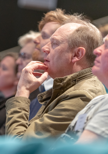 Man i publik som tittar med spänning mot en scen. Mannen syns i profil